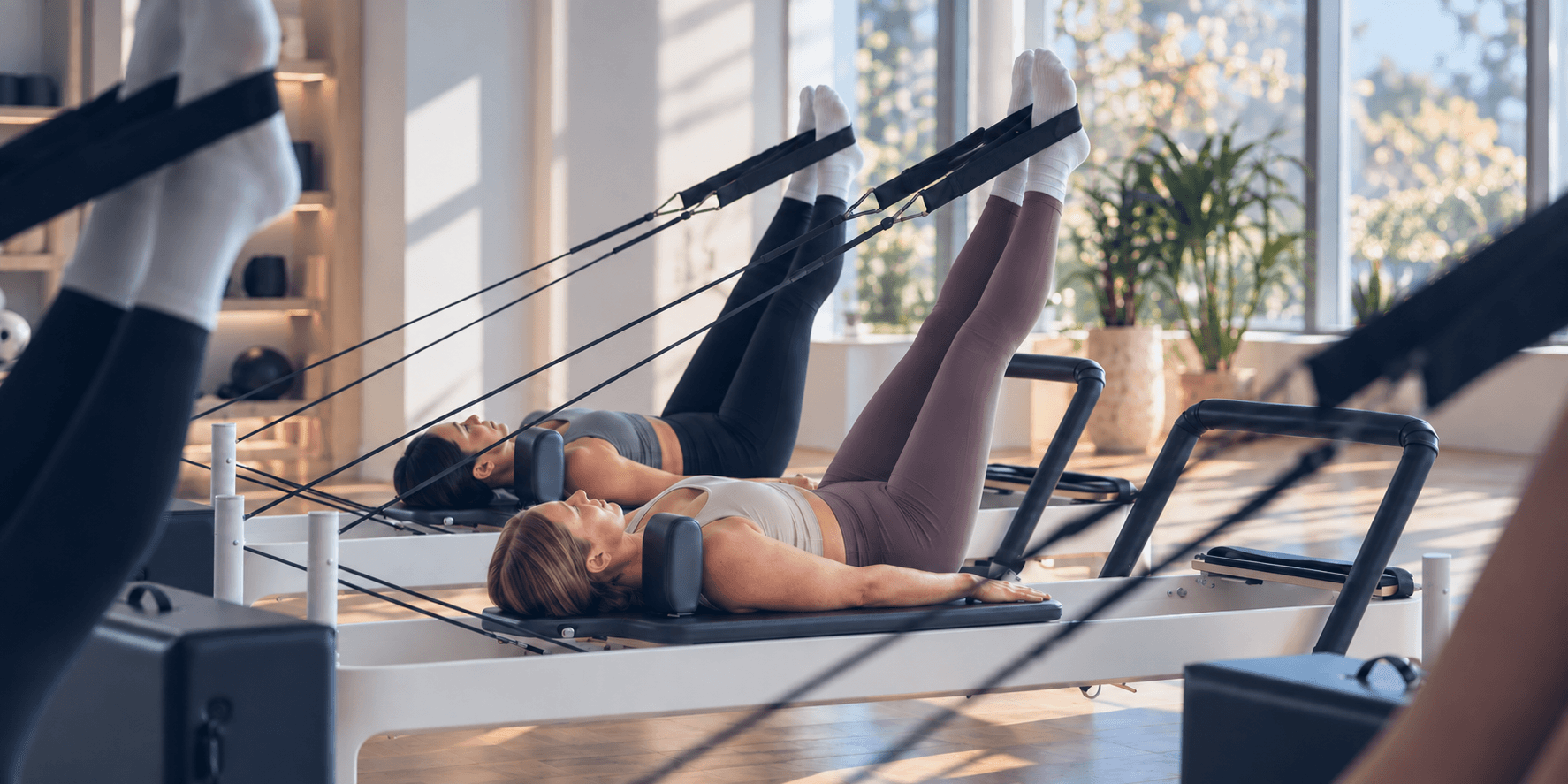 Clients exercise on Reformers in a bright, professionally equipped studio.
